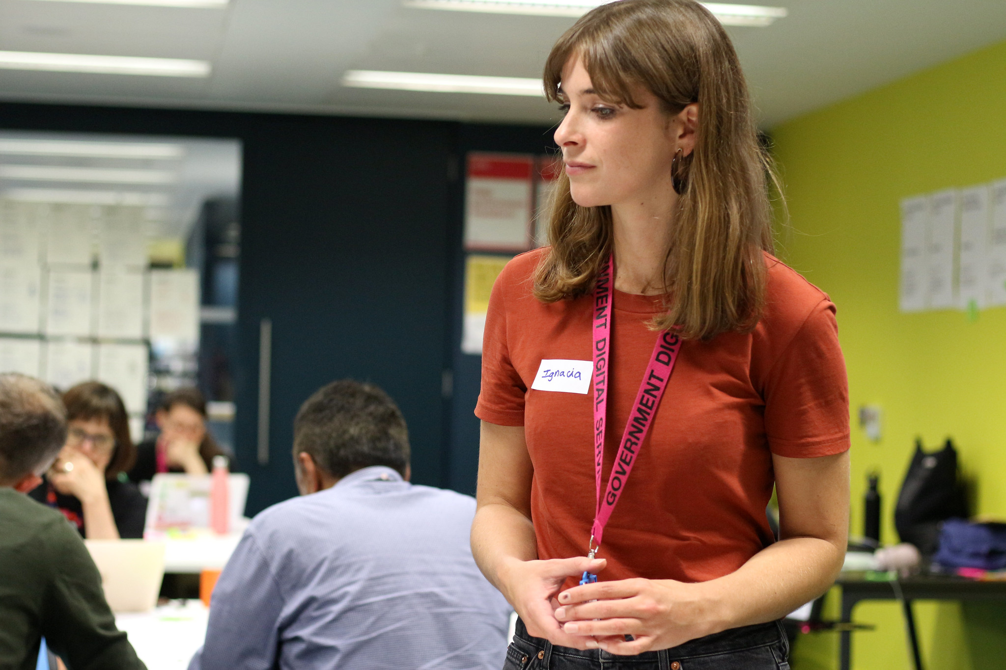 A photo of me  facilitating a workshop, wearing an orange top, a name badge that says 'Ignacia', and a magenta lanyard from the Government Digital Service